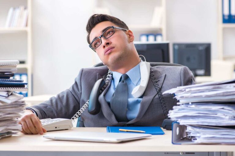 Ragazzo giovane affranto davanti a una scrivania piena di fogli