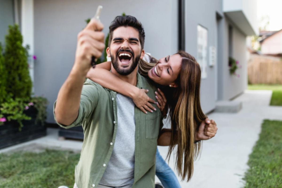 uomo che esulta con in mano delle chiavi e donna che lo abbraccia da dietro