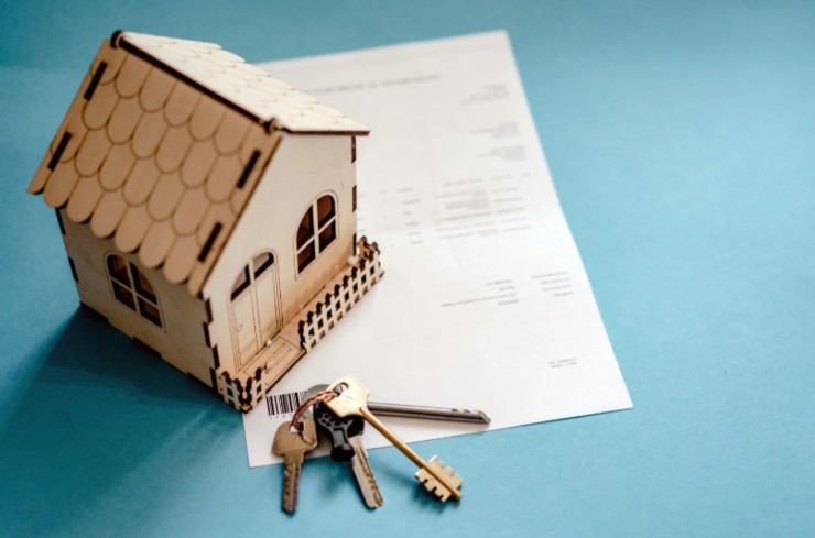 casetta in miniatura accanto ad un foglio e ad un mazzo di chiavi